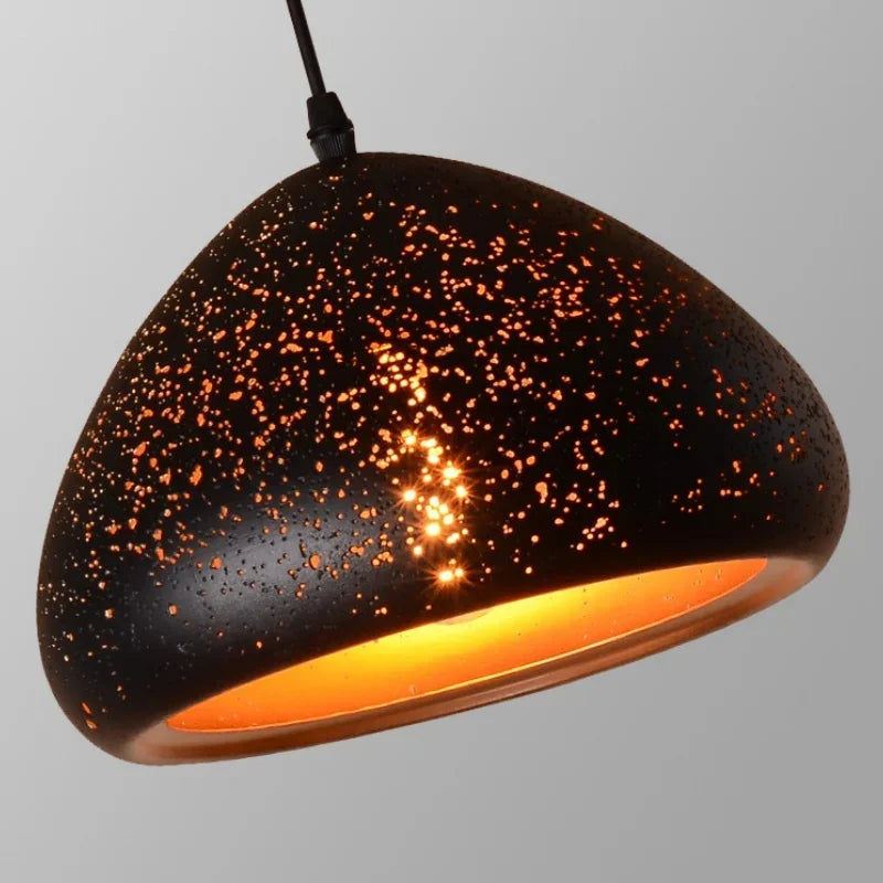 Gros plan sur l'abat-jour d'une suspension constellation perforée en métal noir et doré, style moderne.
