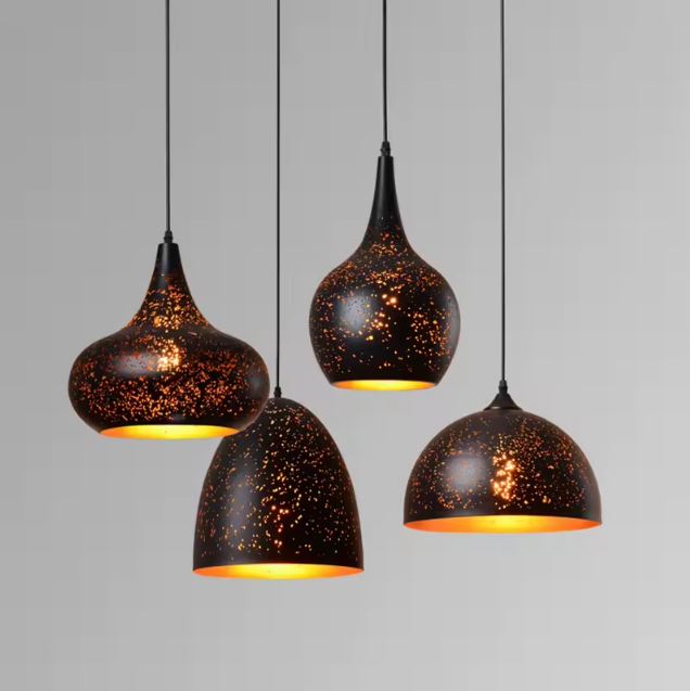 Quatre suspensions en métal noir perforé aux formes organiques, diffusant une lumière étoilée d'inspiration orientale.
