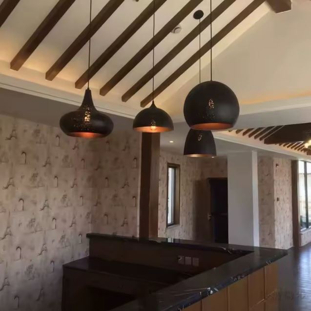 Suspensions en métal noir perforé aux silhouettes variées, apportant un esprit industriel et oriental à un îlot de cuisine.