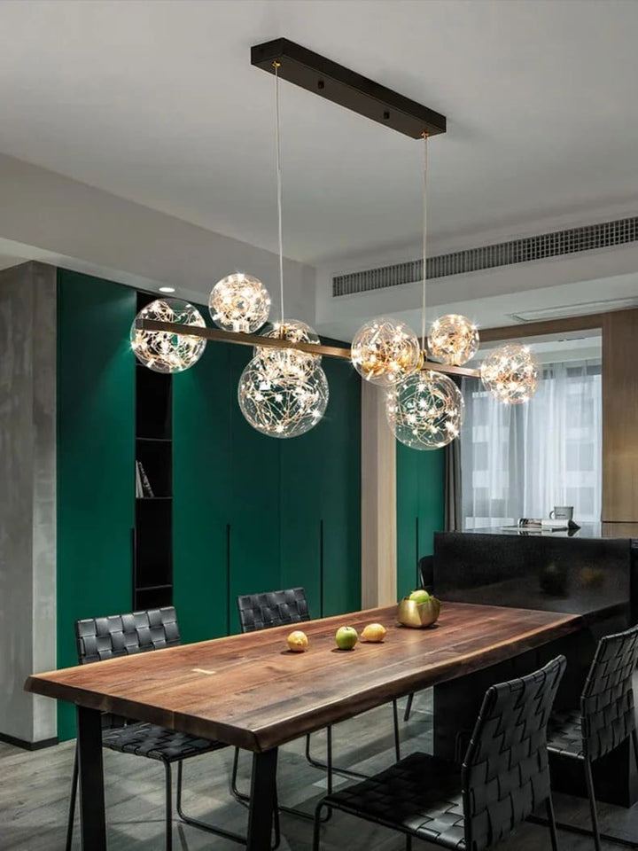 Suspension constellation en verre installée dans une salle à manger au mur vert profond