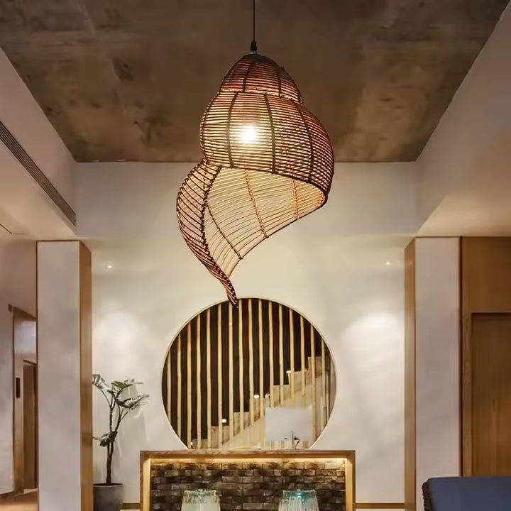 Au centre d’une entrée contemporaine, cette suspension en rotin tressé affiche une silhouette organique et sculpturale