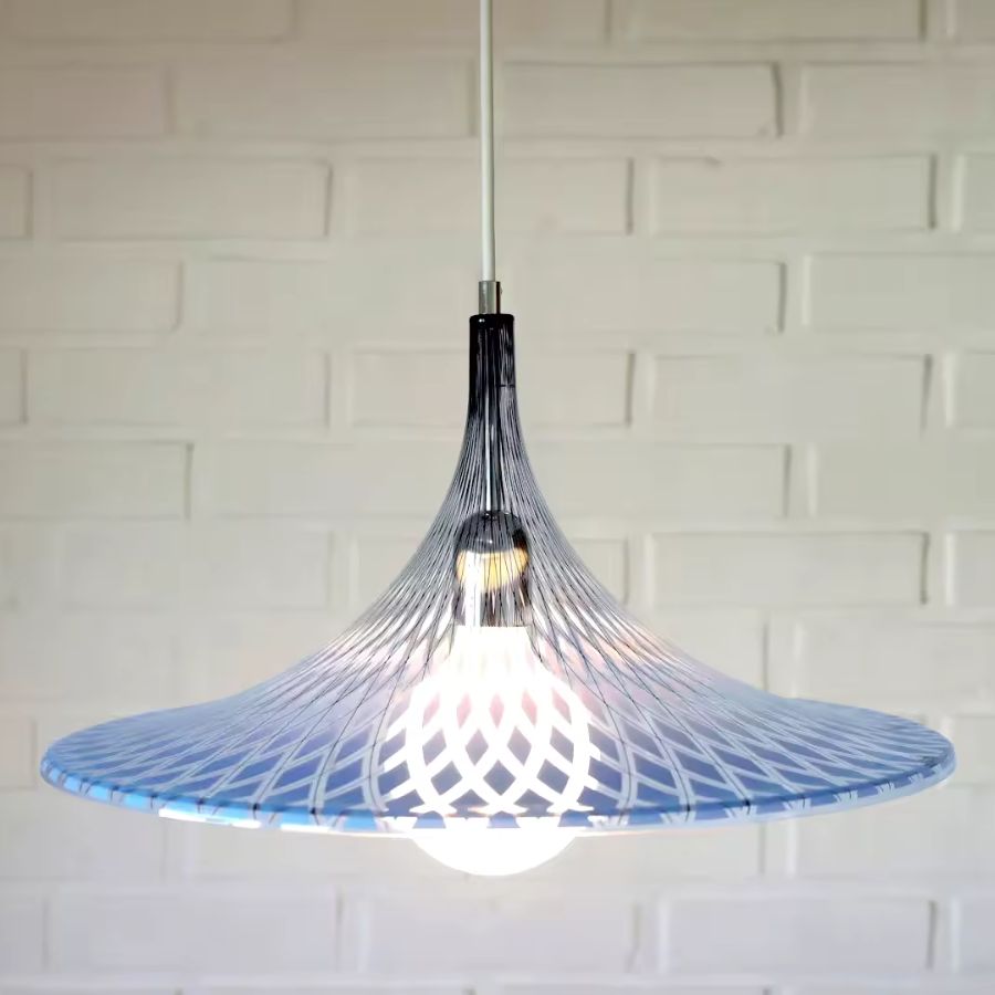Éclairée de face, la suspension corolle en acrylique bleu révèle un motif graphique au style design et contemporain