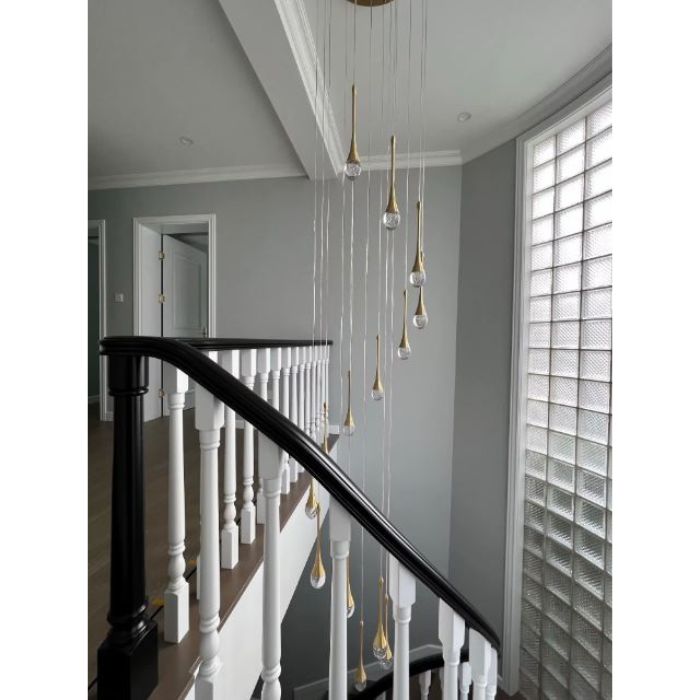 Suspension cristal doré élégante descendant le long d’un escalier blanc, idéale pour sublimer un intérieur lumineux et raffiné.
