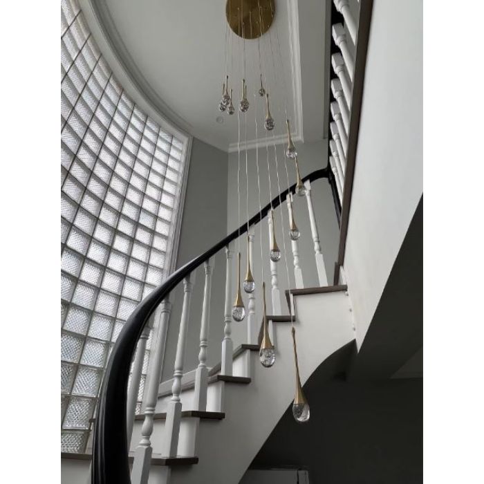 Suspension cristal doré accompagnant un escalier en colimaçon, idéale pour créer une mise en lumière élégante sur grande hauteur.