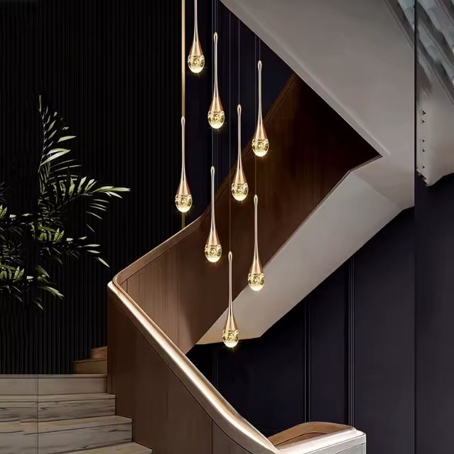 Suspension cristal doré en cascade goutte à goutte, idéale pour habiller un escalier moderne ou un intérieur à plafond très haut.
