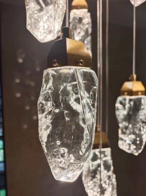 Détail de suspension cristal effet glace et diamant, luminaire de luxe contemporain aux reliefs minéraux et reflets scintillants.