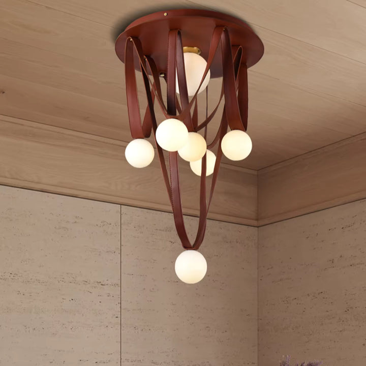 Sous un plafond chaleureux, les lanières de cuir brun et les globes opalins composent une suspension au style organique.