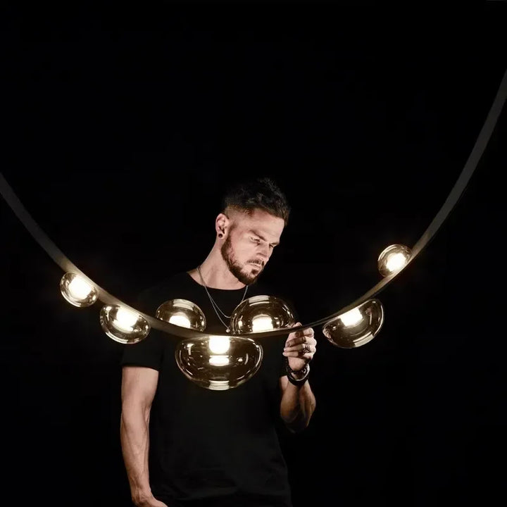 Mise en situation de la suspension en cuir noir et sphères lumineuses montrant son envergure remarquable.