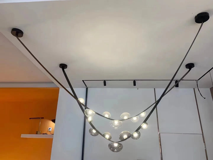 Suspension tendance en cuir noir et sphères lumineuses fumé créant une ambiance graphique et élégante.