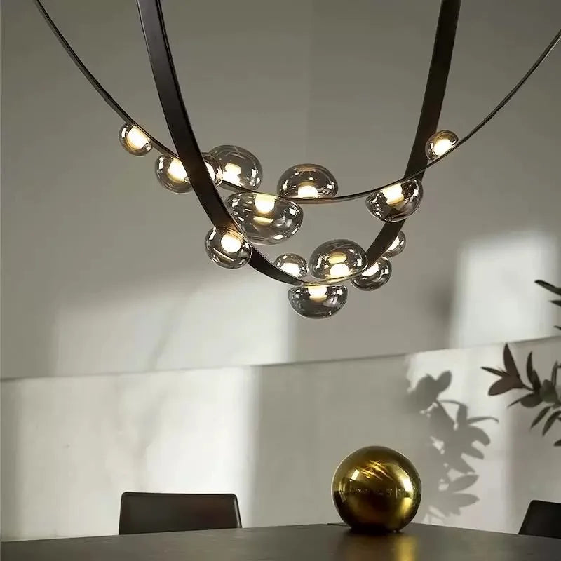 Suspension design en cuir noir et sphères lumineuses suspendues en verre fumé, idéale au-dessus d'une table à manger moderne.