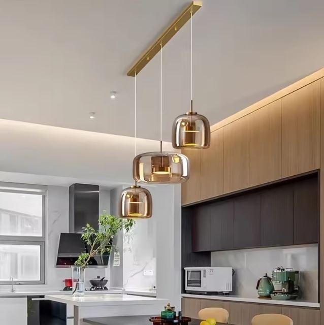 Suspension dorée en verre ambré style contemporain, idéale au-dessus d’un îlot central dans une cuisine moderne ou minimaliste chic.