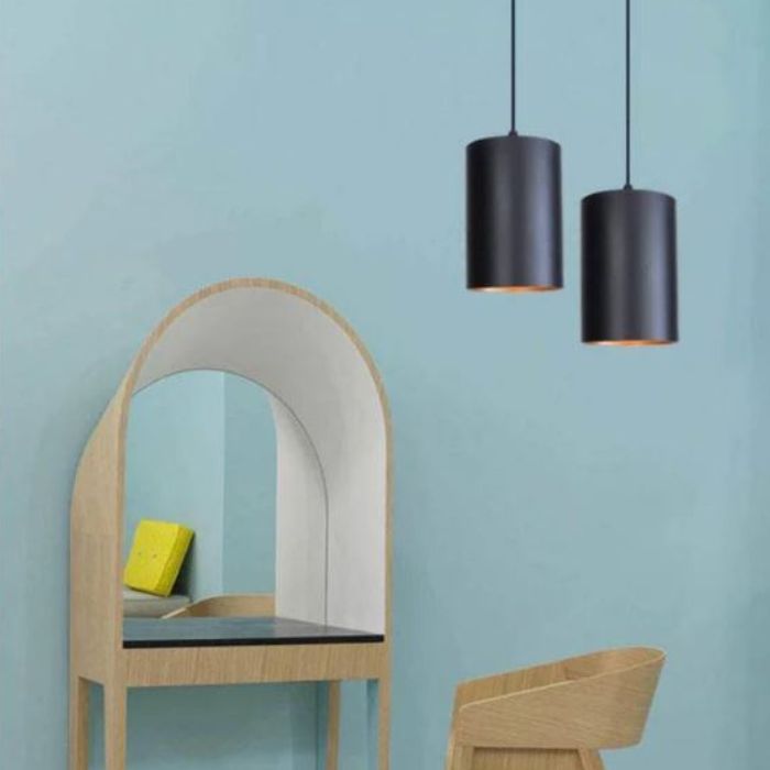 Suspension cylindrique noire moderne, combinée avec un mobilier en bois clair pour un style scandinave épuré.