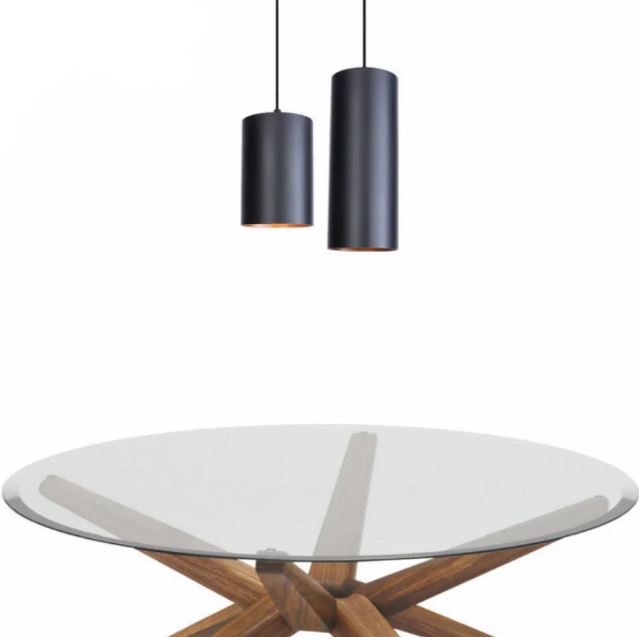 Suspension cylindrique noire élégante, suspendue au-dessus d'une table en verre moderne avec base en bois sculpté.