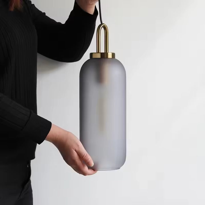 Vue à l’échelle d’une suspension cylindrique en verre fumé à anse dorée au design élégant et contemporain