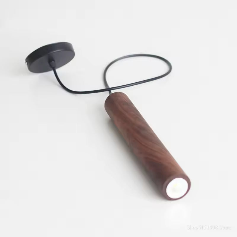 Luminaire cylindrique en bois foncé avec câble noir, au design moderne sobre et graphique