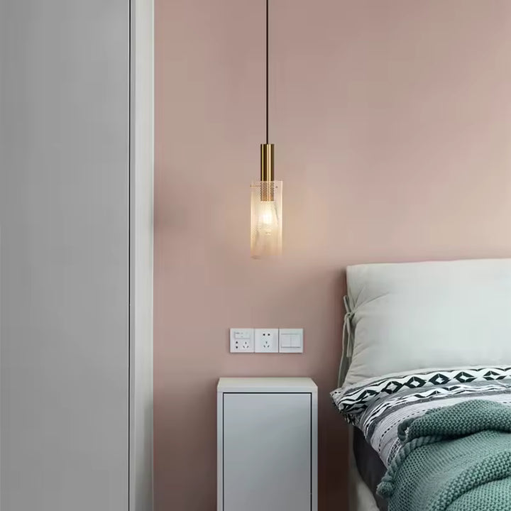 Près du lit, cette suspension cylindrique dorée au métal ajouré apporte une touche moderne et minimaliste à la chambre