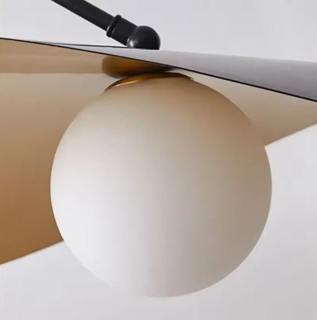 Détail d’une suspension déportée avec globe opalin, abat-jour finition noire et dorée au style moderniste.