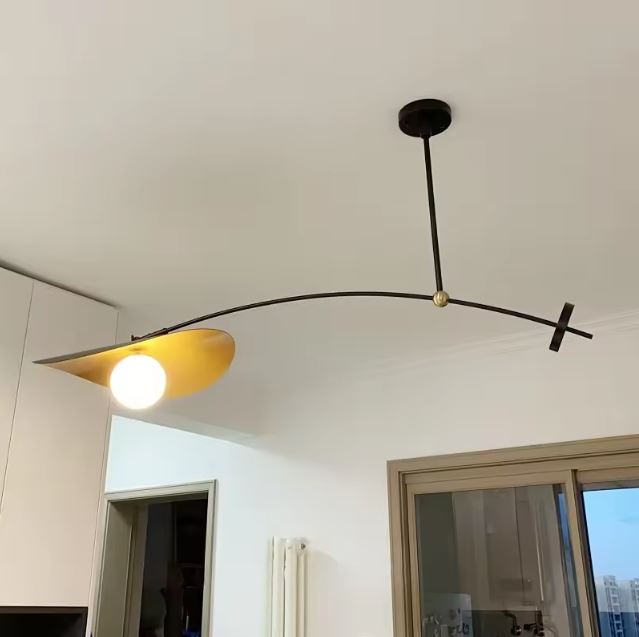 Suspension déportée noire et dorée à bras arqué, avec globe lumineux et allure design rétro 70 moderne.