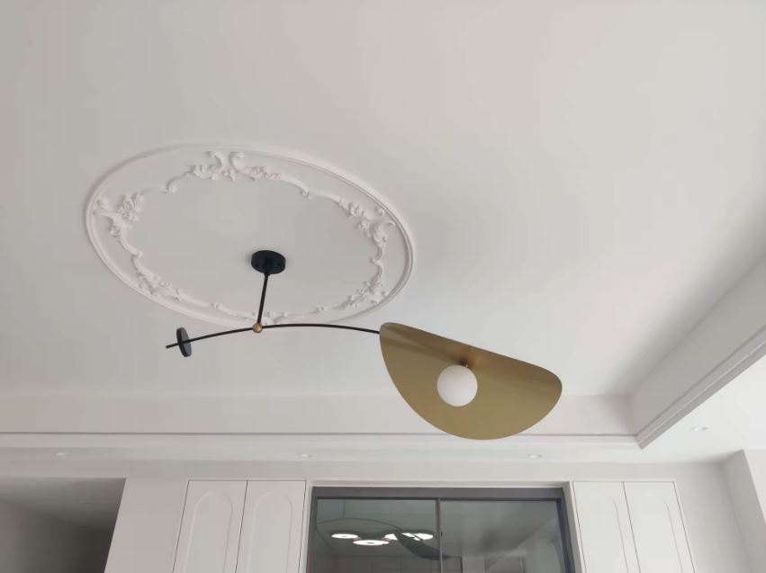 Suspension déportée noire et dorée avec globe blanc, au style design et graphique vue au plafond.