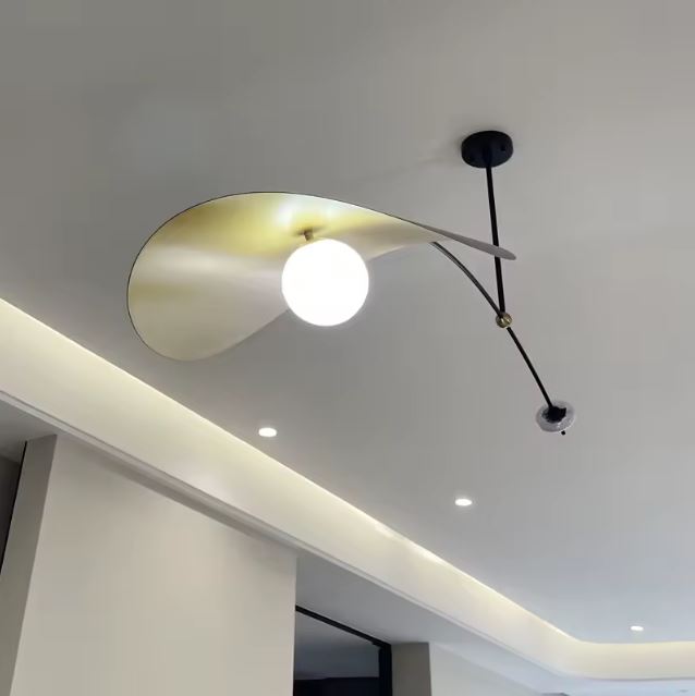 Vue dessous d’une suspension déportée noire et dorée avec globe blanc, au style chic et design.