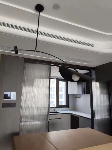 Suspension déportée noire avec globe blanc, dans une cuisine au style design et architectural.