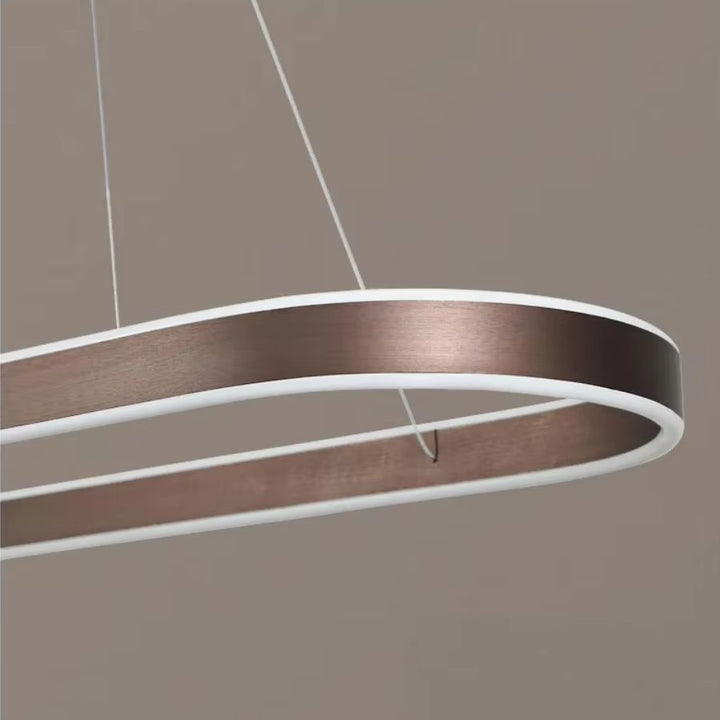 Gros plan sur la finition café en métal brossé d'une suspension ovale allongée, aux courbes épurées et au style contemporain.