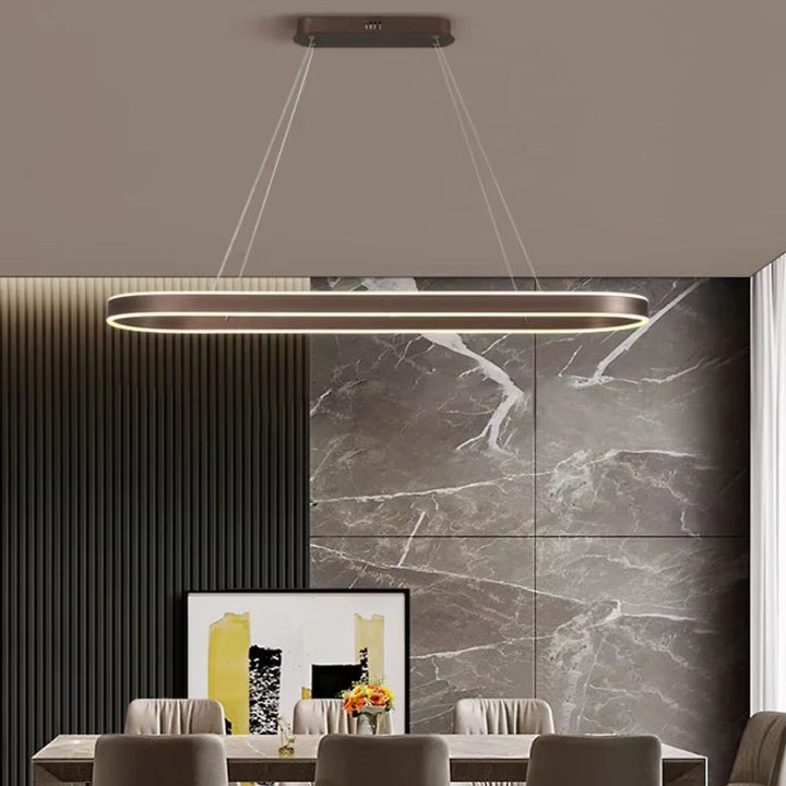 Suspension LED à anneau ovale allongé finition café, au design moderne et raffiné, devant un mur en marbre gris.