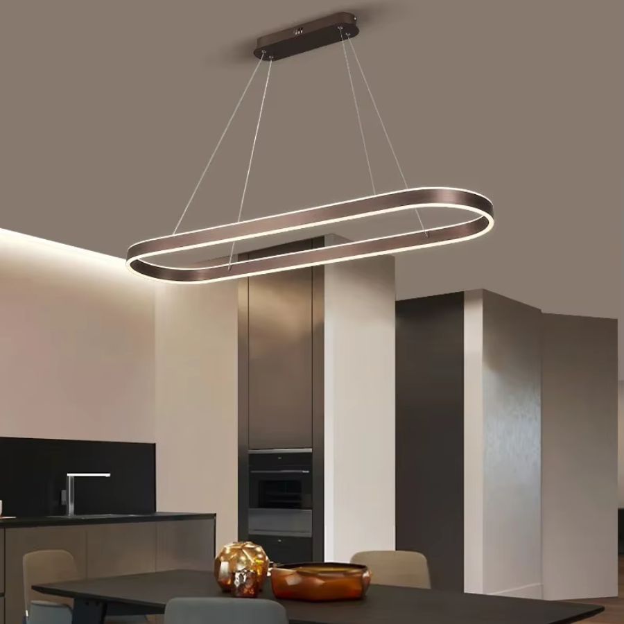 Luminaire LED à anneau ovale allongé finition café, au style minimaliste chic, suspendu au-dessus d'une table à manger.