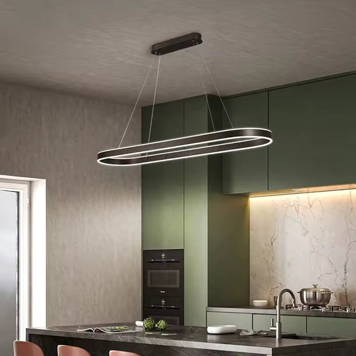 Éclairage LED d'une suspension noire à anneau ovale allongé, au style minimaliste, surplombant un îlot de cuisine moderne.