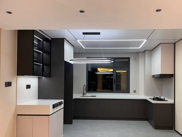 Dans une cuisine moderne aux tons noirs et blancs, suspension LED à anneau ovale allongé au design géométrique épuré.