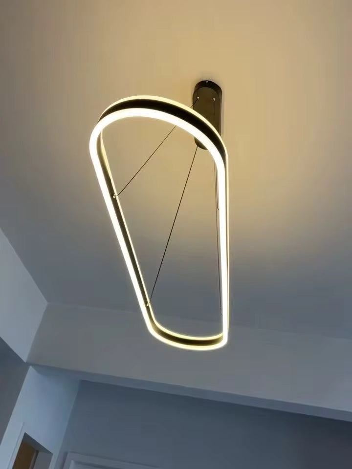 Vue du dessous d'une suspension noire à anneau ovale allongé, diffusant une lumière LED chaude au design contemporain épuré.