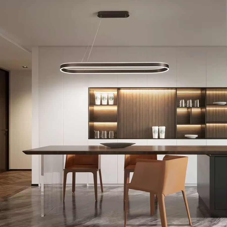 Une suspension LED noire à anneau ovale allongé illumine une table à manger, dans un intérieur contemporain aux lignes épurées.