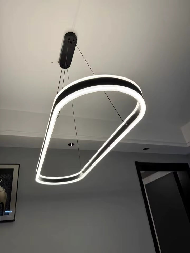 Vue en contre-plongée d'une suspension LED noire à anneau ovale allongé, aux courbes lumineuses et au design futuriste.