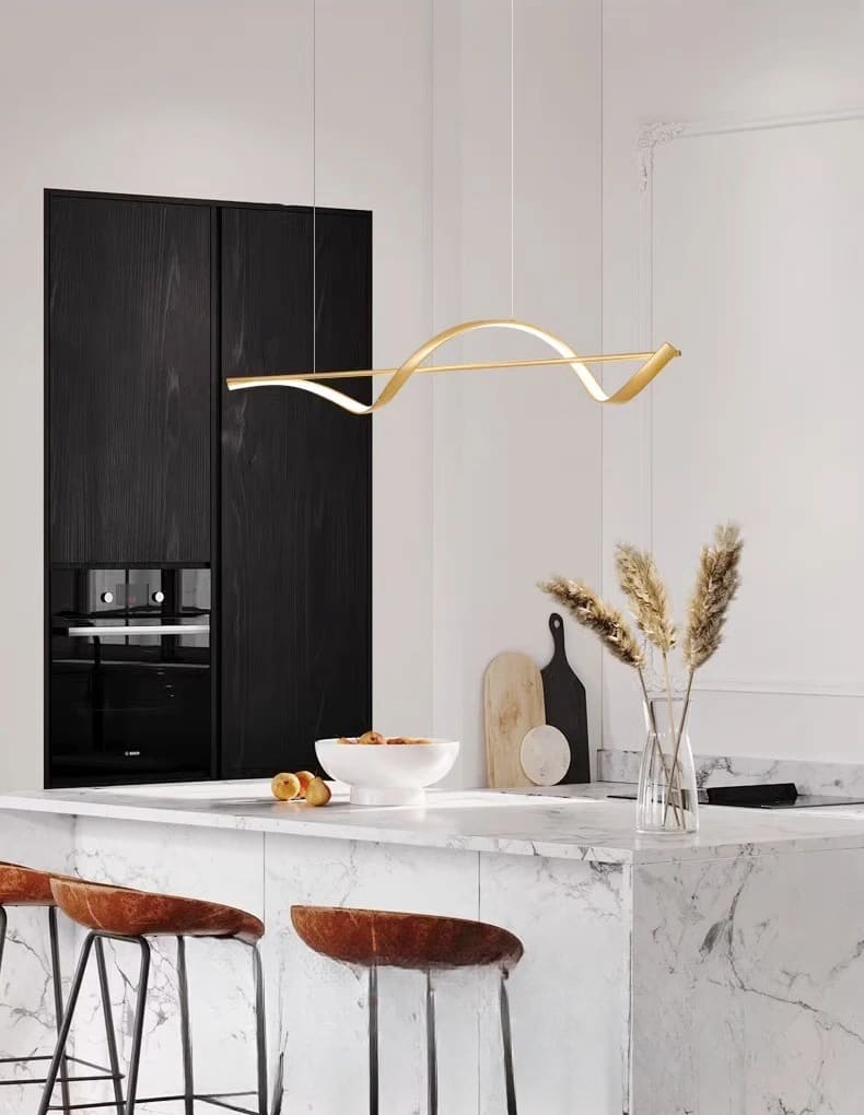 Suspension au design artistique avec un ruban doré installée au cœur d'une cuisine moderne.