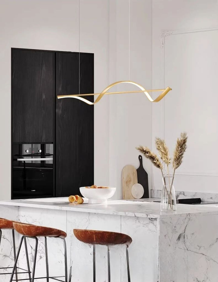 Suspension au design artistique avec un ruban doré installée au cœur d'une cuisine moderne.
