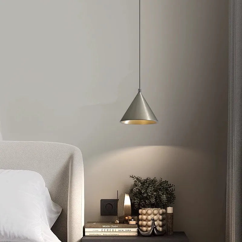 Suspension design conique en métal brossé, idéale pour un éclairage d'ambiance raffiné au-dessus d'une table de chevet.