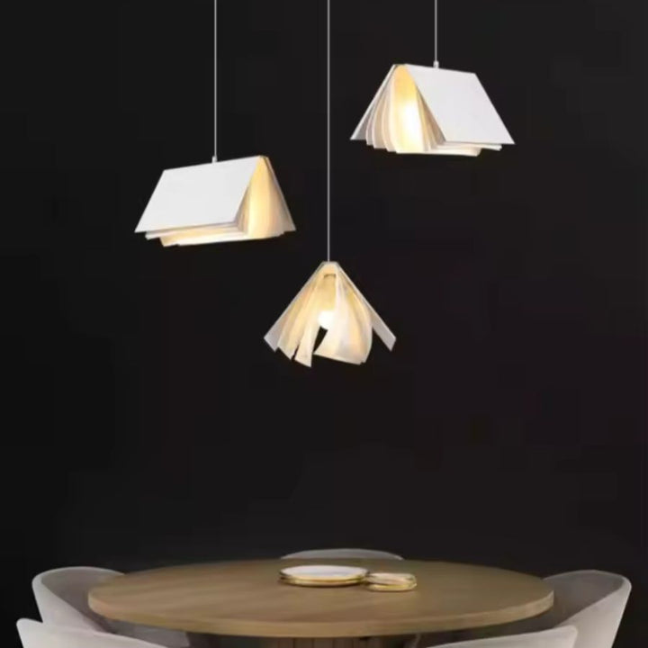 Trio de suspensions design en forme de livre ouvert au-dessus d’une table, dans un style minimaliste et contemporain