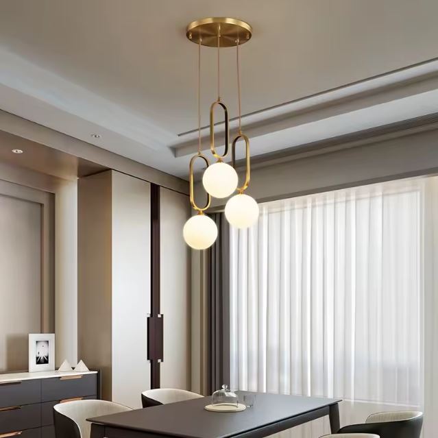 Suspension design en laiton avec globes en verre opalin, luminaire élégant d’inspiration art déco pour intérieur contemporain lumineux.
