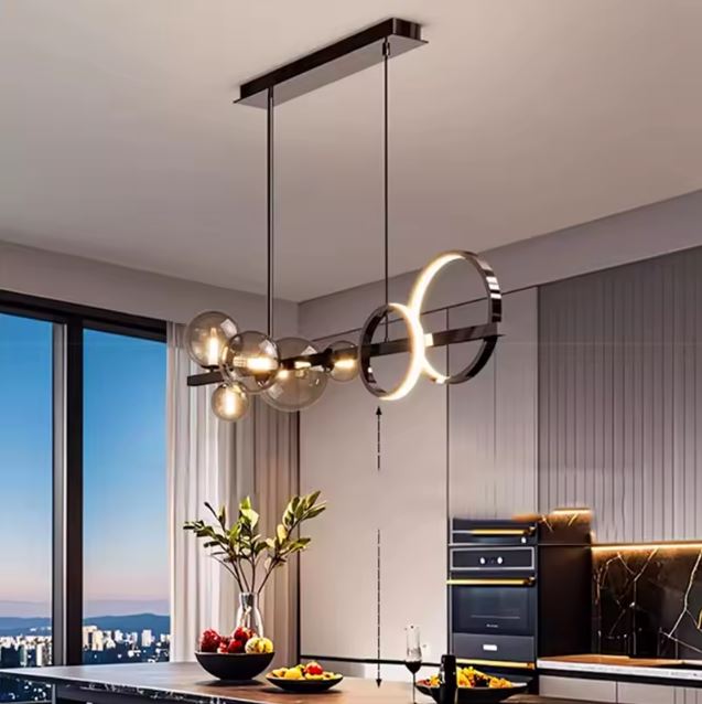 Suspension design avec anneaux LED et globes en verre fumé, offrant un éclairage moderne et sculptural au-dessus d’un plan de travail contemporain.