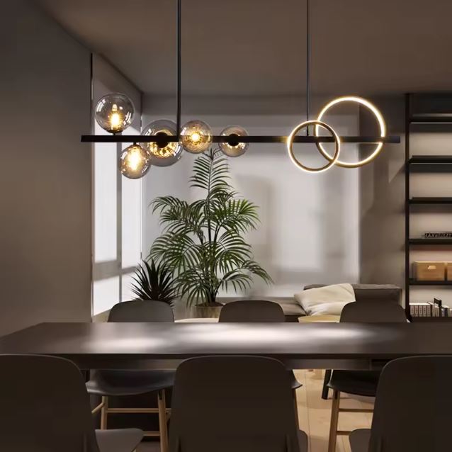 Suspension design avec globes en verre fumé et anneaux LED, éclairant une salle à manger moderne décorée de plantes et de mobilier aux lignes contemporaines et chic.