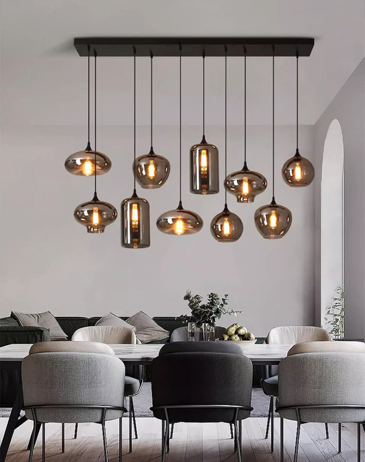 Suspension design multiple en verre fumé installée dans une salle à manger au mobilier moderne.