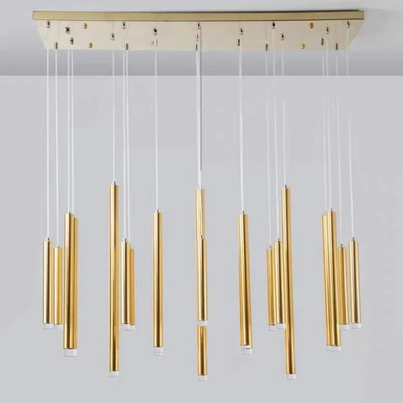 Suspension design à tubes lumineux dorés disposés en grappe sur fond neutre.