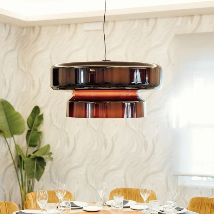 Suspension au design italien en verre fumé brun installée au-dessus d'une table de salle à manger lumineuse.
