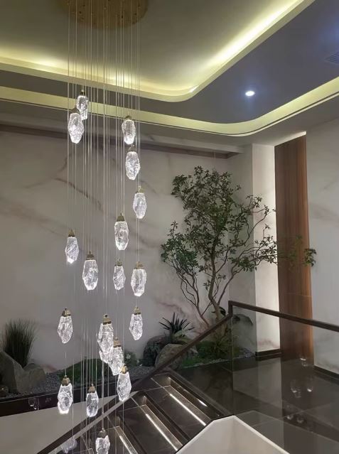 Une suspension diamant en cascade de cristaux, illuminant l’escalier moderne et sublimant le décor végétal intérieur.