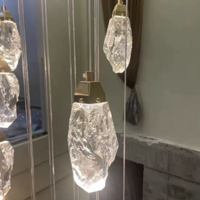 Gros plan sur une suspension diamant en verre type cristal facetté, révélant l’éclat et la finesse des pendentifs lumineux.