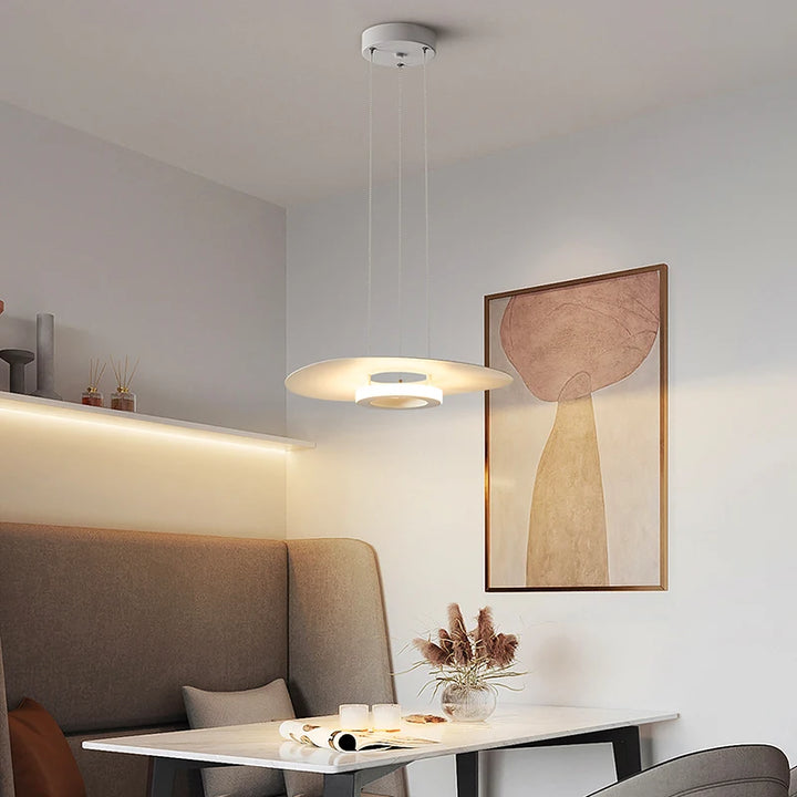 Suspension disque blanc à halo lumineux suspendue au-dessus d'une banquette de coin repas cosy.
