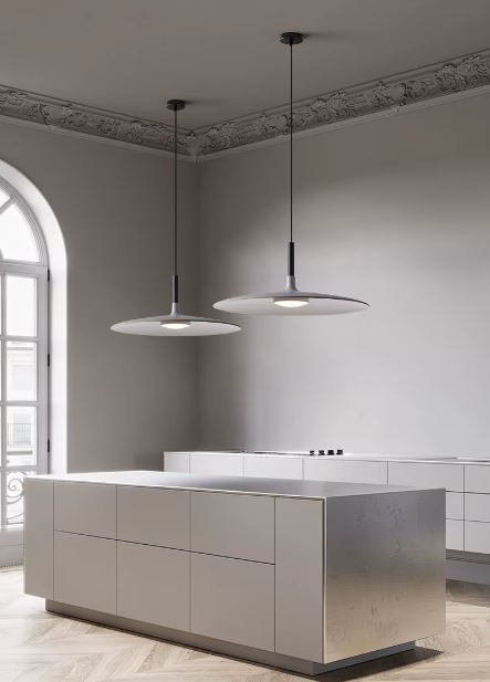 Deux suspensions disque blanches au-dessus d'un îlot de cuisine dans un intérieur minimaliste et contemporain