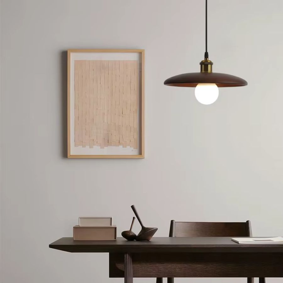 Dans une salle à manger épurée, cette suspension en bois foncé et globe lumineux affirme un style japandi contemporain