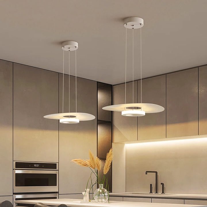 Double suspension disque blanc mat à halo lumineux au design moderne dans une cuisine épurée.