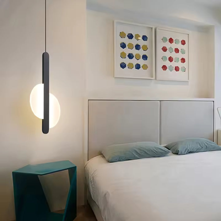 Luminaire suspendu noir à disque lumineux près du lit dans une chambre design au style moderne et graphique